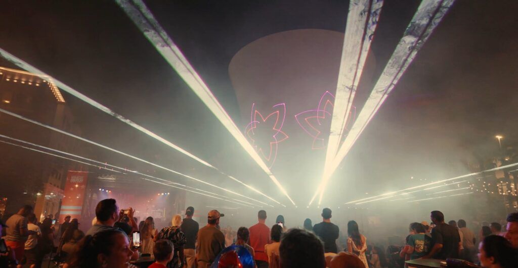 Pink lotus laser graphic with crowd watching from below